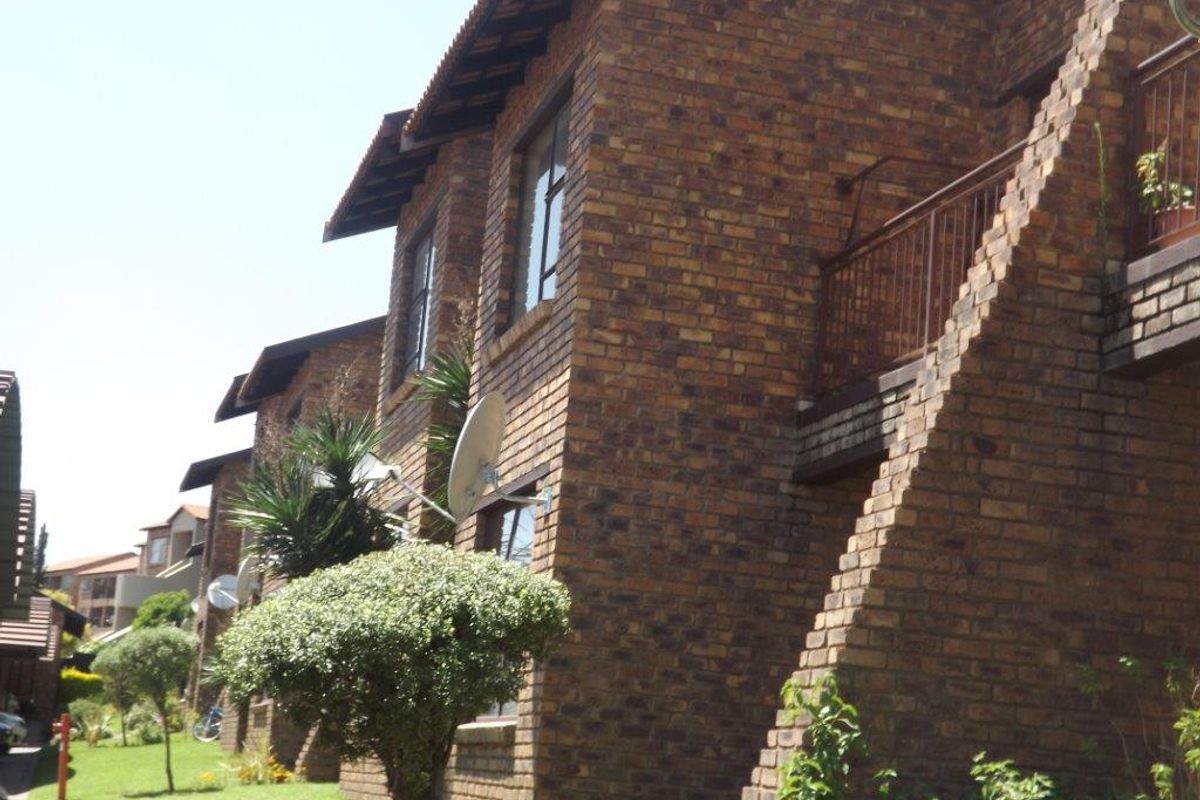 Exterior view of a multi-story apartment complex featuring face brick construction, tiled roofing, and private balconies.