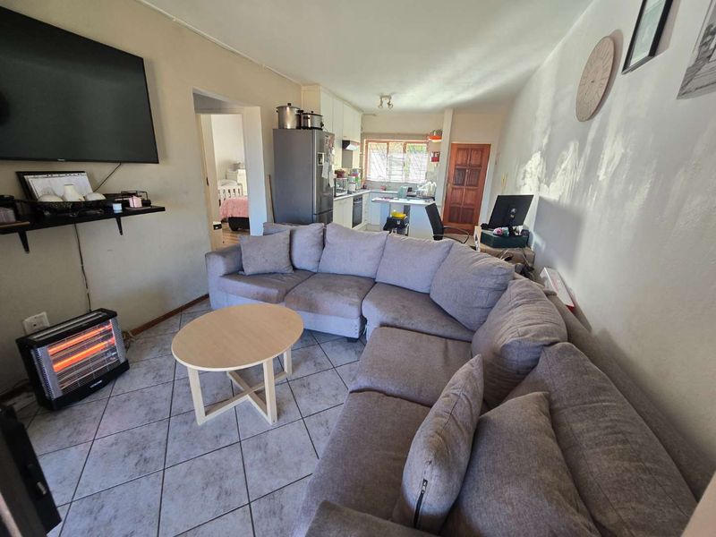Open-plan living area featuring tiled flooring and a functional kitchen space with built-in cabinetry, providing a versatile layout for daily living.