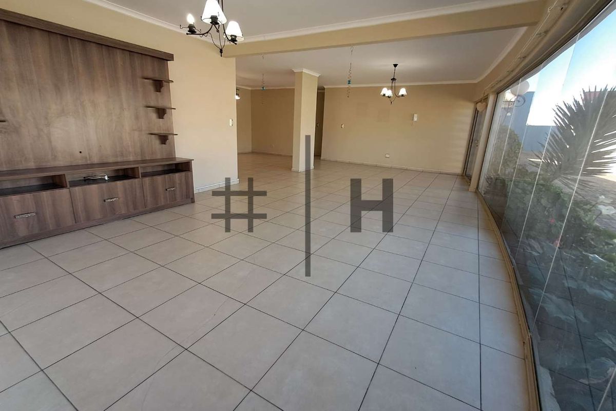Spacious open-plan living area featuring tiled flooring, built-in cabinetry, and large glass sliding doors providing ample natural light.