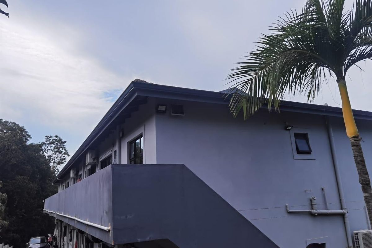 Exterior view of the apartment building featuring a balcony, external staircase, and painted facade.