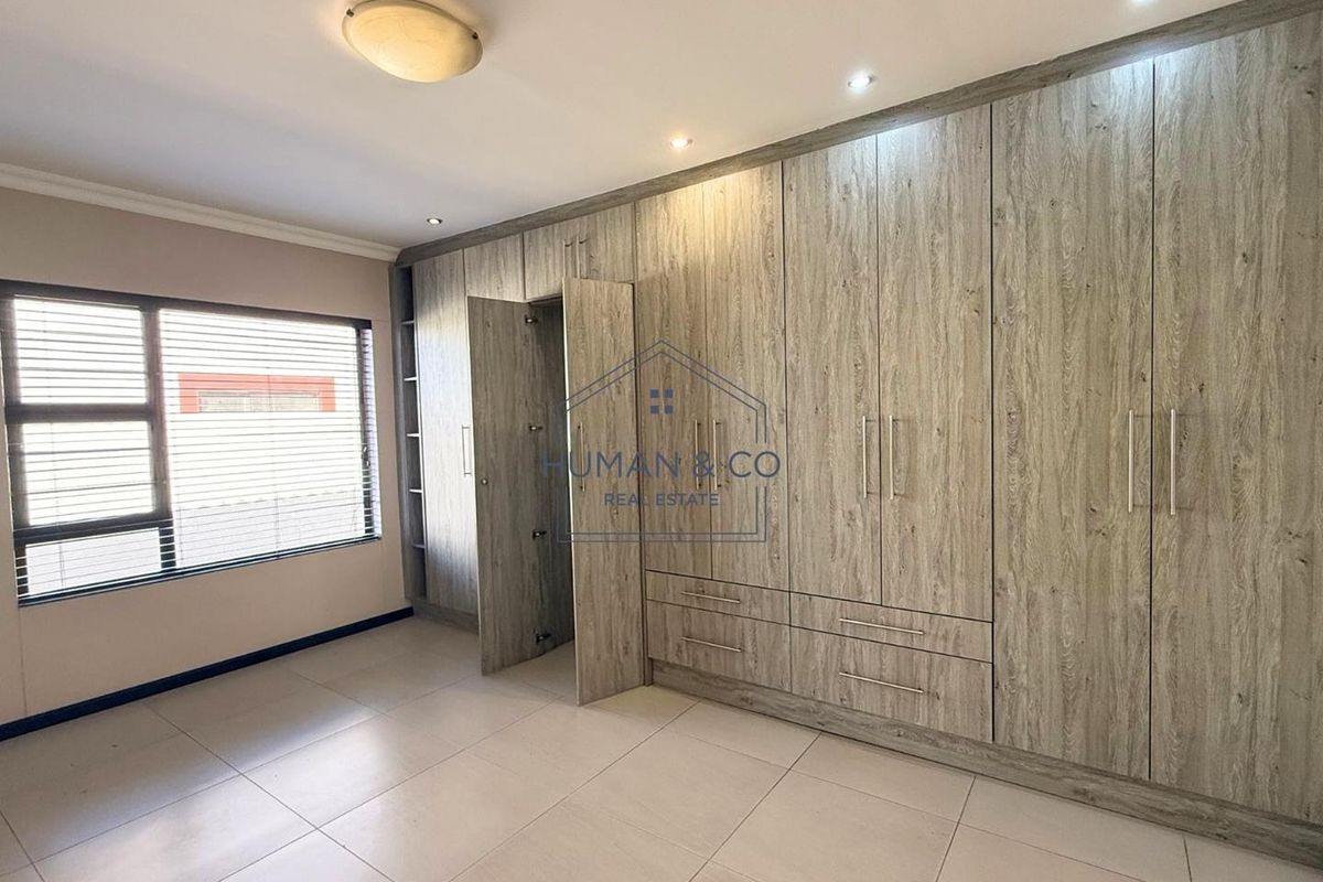 A bright bedroom featuring extensive built-in wooden cabinetry with integrated storage and tiled flooring.
