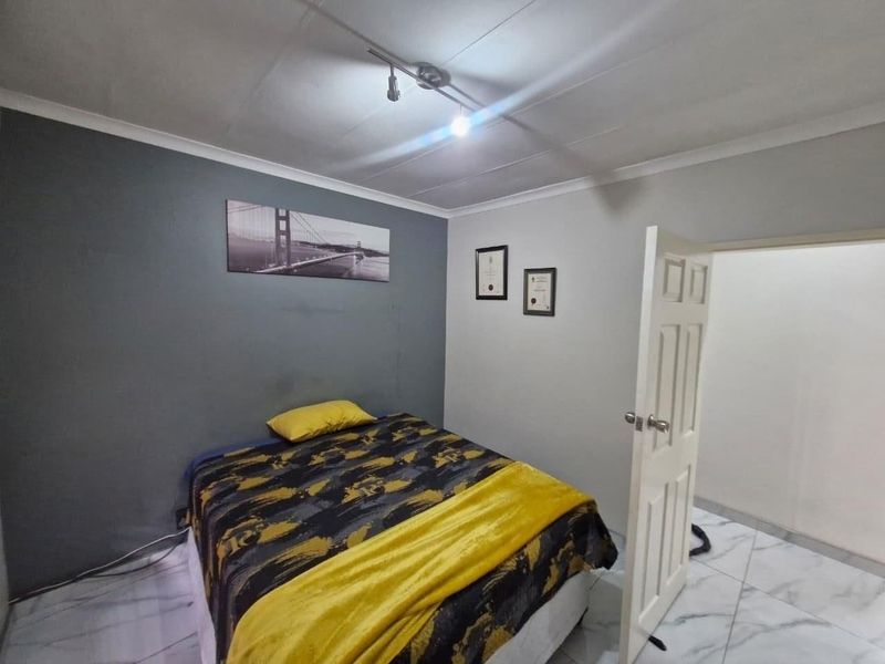 A bedroom featuring tiled flooring, cove cornicing, and track lighting, providing a functional space with neutral wall finishes.
