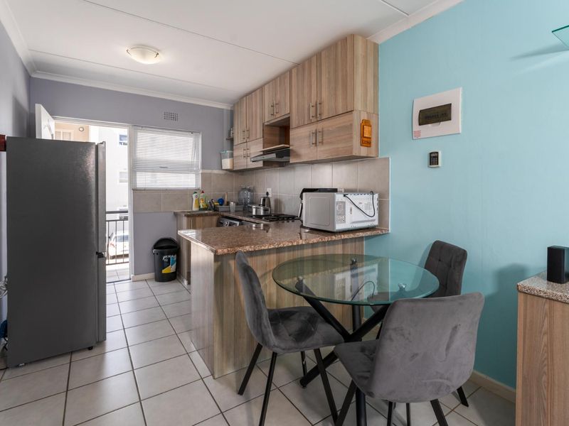 Compact kitchen featuring laminate cabinetry, granite countertops, tiled backsplash, and direct access to an outdoor balcony area.