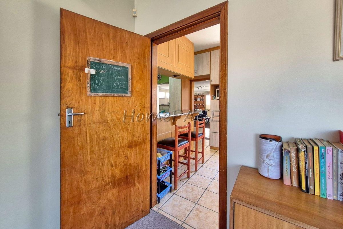 View through a wooden door into a kitchen area featuring tiled flooring and built-in cabinetry.