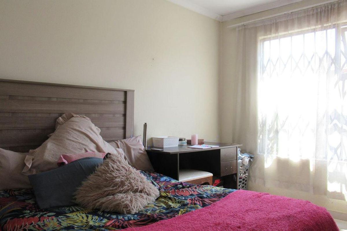 A bedroom featuring a window with a security gate and neutral wall finishes.