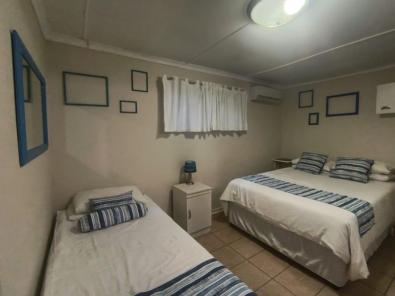 A functional bedroom featuring tiled flooring, a wall-mounted split-system air conditioner, and neutral wall finishes.