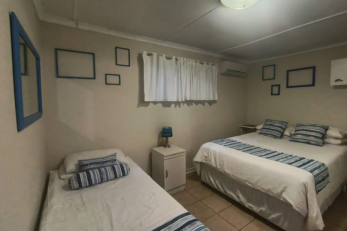 A functional bedroom featuring tiled flooring, a wall-mounted split-system air conditioner, and neutral wall finishes.
