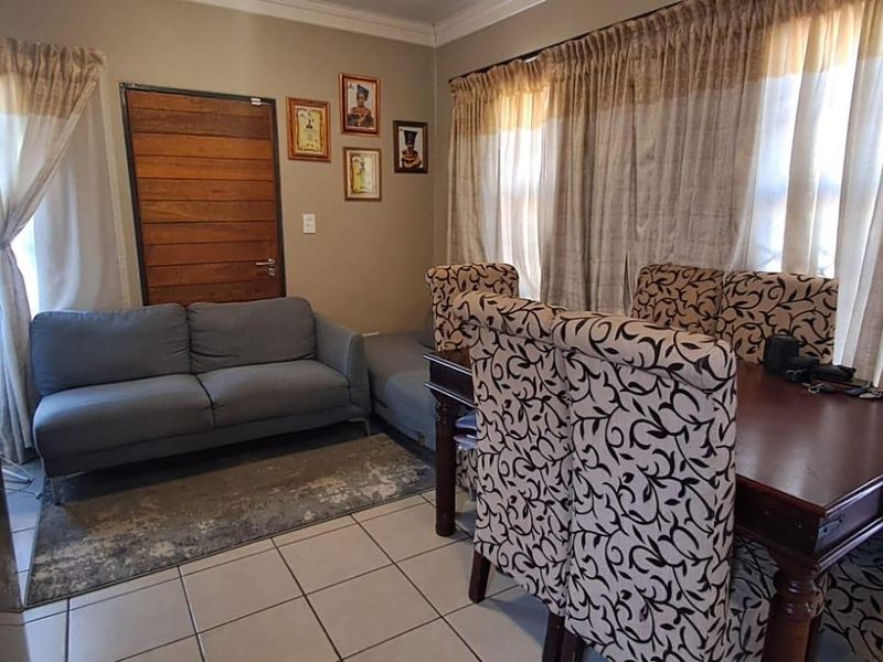 An open-plan living and dining area featuring tiled flooring and a wooden entrance door, providing a functional space for daily living.