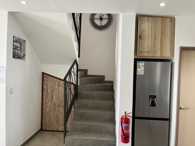 A functional hallway featuring a tiled staircase with a metal balustrade and convenient under-stair storage cabinetry.