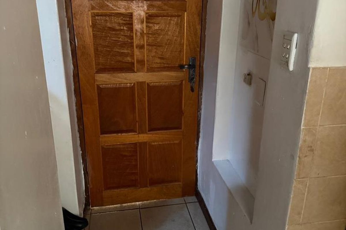 A functional entryway featuring a solid wooden door, ceramic tiled flooring, and a recessed wall niche for storage or display.