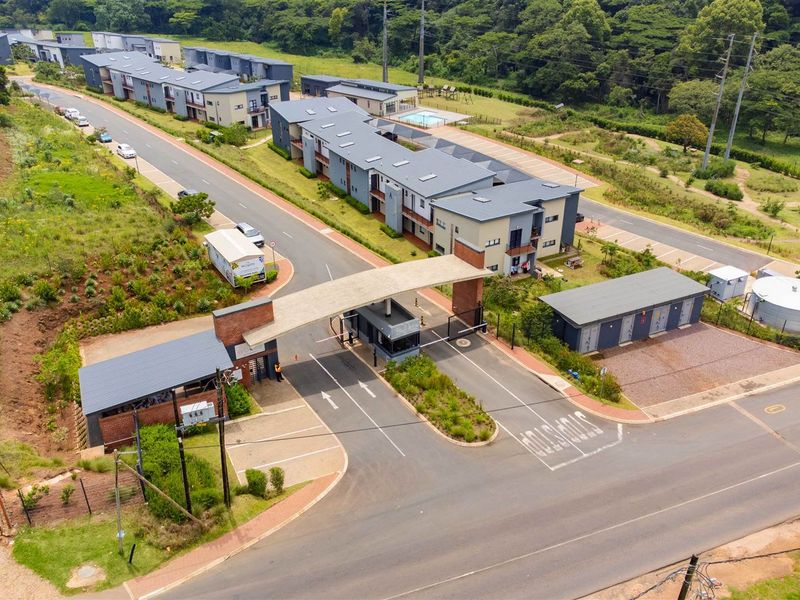 Aerial view of a secure residential apartment complex featuring a gated entrance, paved access roads, and landscaped grounds.
