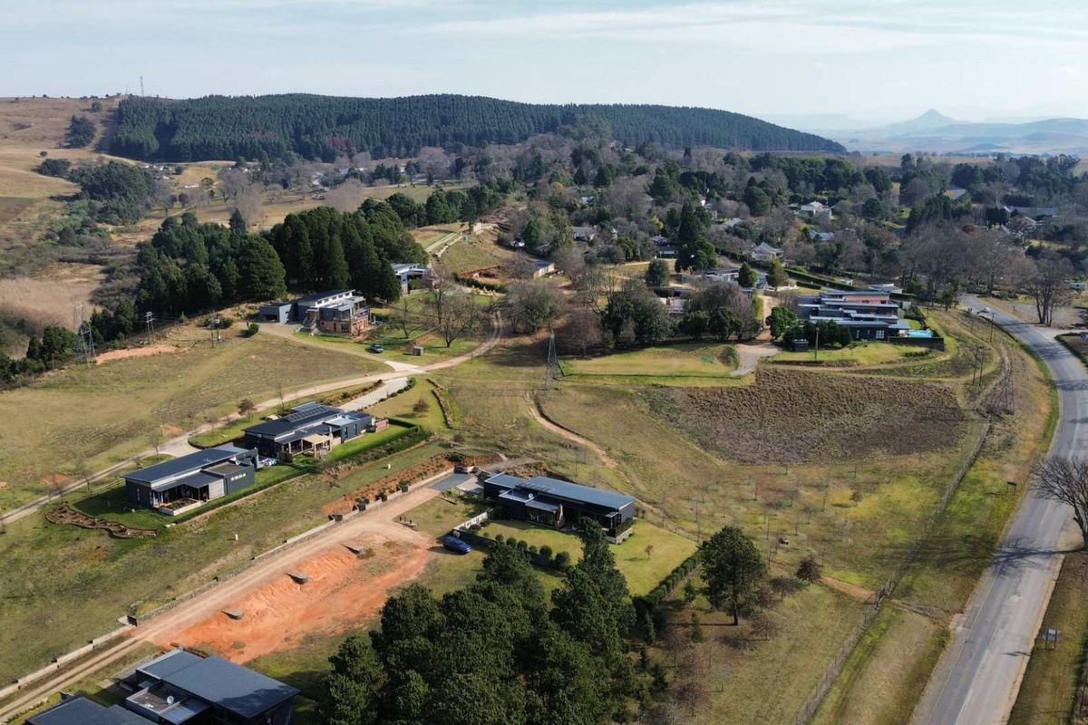 An aerial view of a residential estate featuring modern homes, established trees, and surrounding rural landscape.