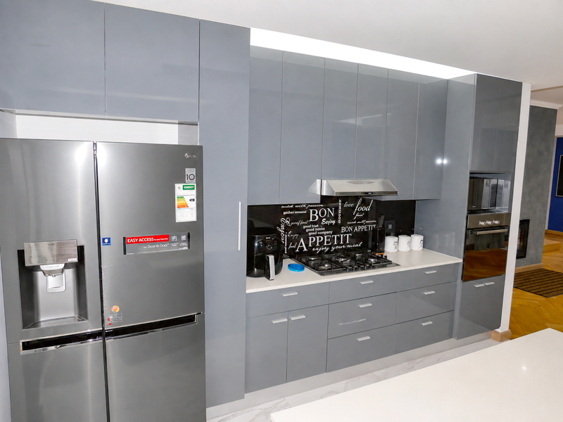Modern kitchen featuring high-gloss grey cabinetry, integrated appliances including an oven and microwave, gas hob, and sleek stone countertops.