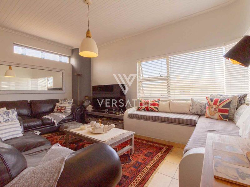 A comfortable living room featuring a built-in window seat, tiled flooring, and a classic tongue and groove ceiling.