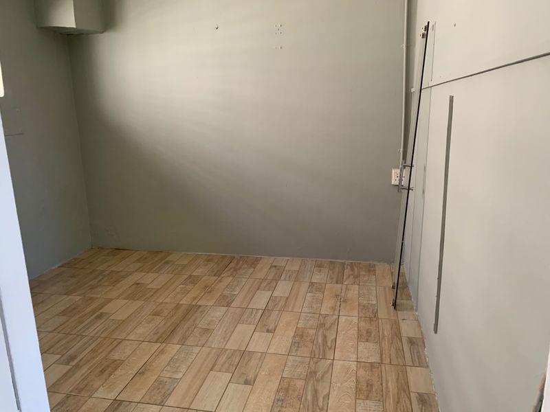 An empty, unfinished room featuring wood-look tile flooring and neutral wall paint, offering a blank canvas for renovation or bedroom conversion.