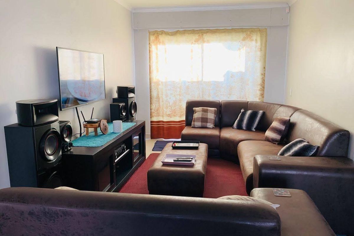 A comfortable living room featuring neutral walls and a large window with natural light, providing a functional space for relaxation.