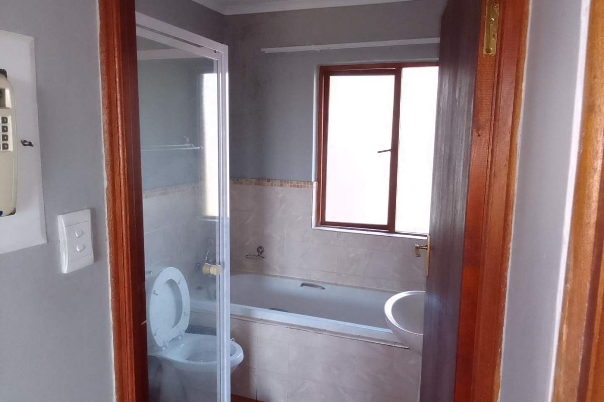 A functional bathroom featuring a built-in bathtub, a separate glass-enclosed shower, and a pedestal basin with neutral wall tiling.