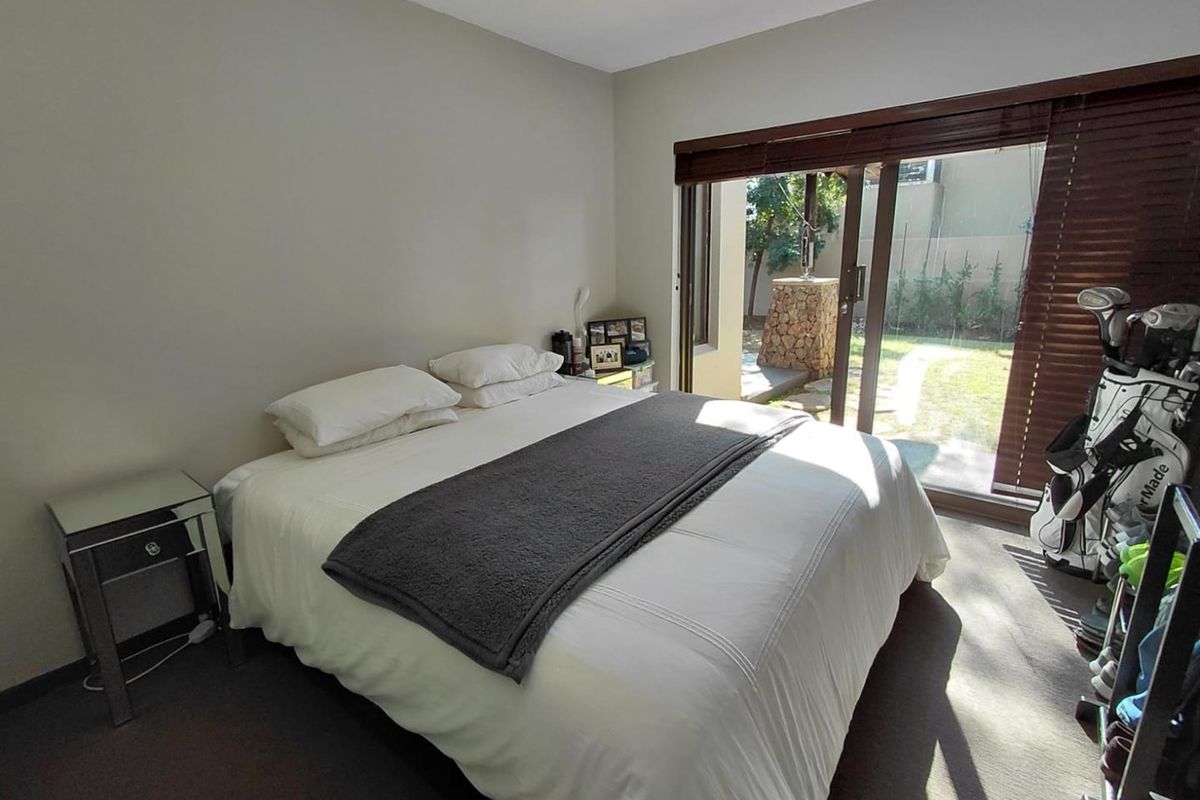 A bedroom featuring neutral walls, carpeted flooring, and a large sliding glass door providing direct access to the rear garden area.