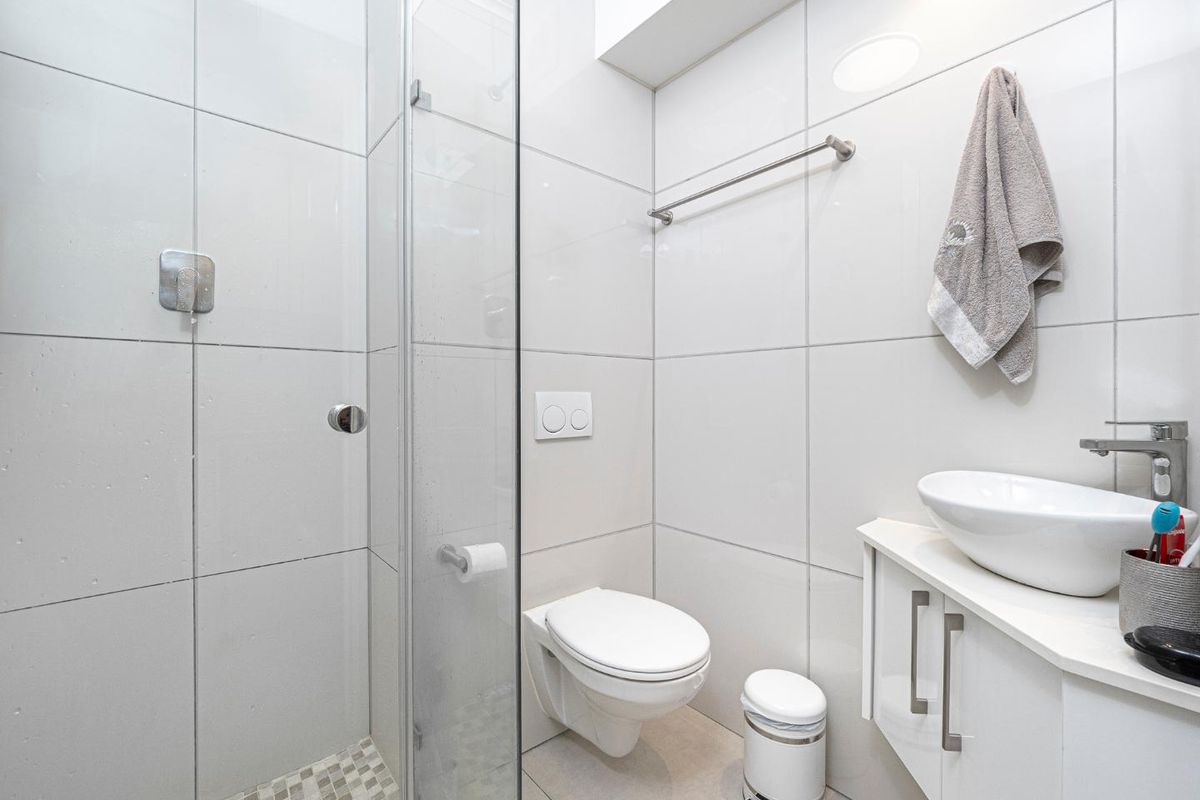 Modern bathroom featuring a glass-enclosed shower, wall-mounted toilet, and a sleek vanity with a vessel sink.