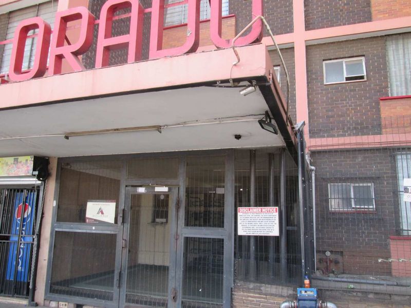 Front entrance of the apartment building featuring a brick facade, metal security gate, and signage.