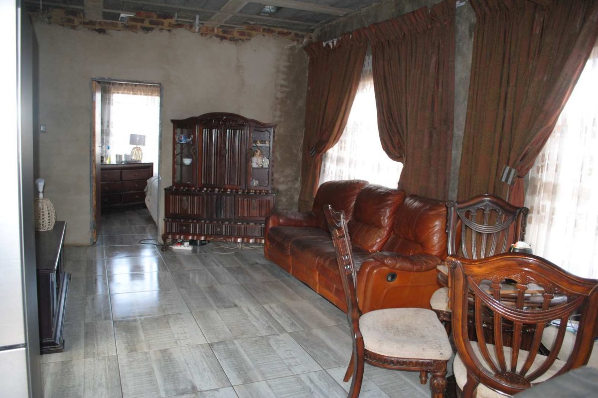 Living area featuring tiled flooring and exposed structural ceiling elements, presenting an opportunity for renovation and finishing.