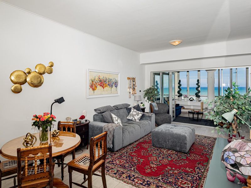 Open-plan living and dining area featuring tiled flooring and large sliding glass doors that open onto a balcony with ocean views.