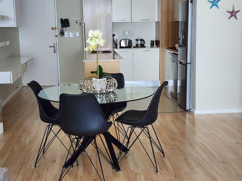 An open-plan living and kitchen area featuring modern built-in cabinetry, laminate flooring, and a functional kitchen layout.