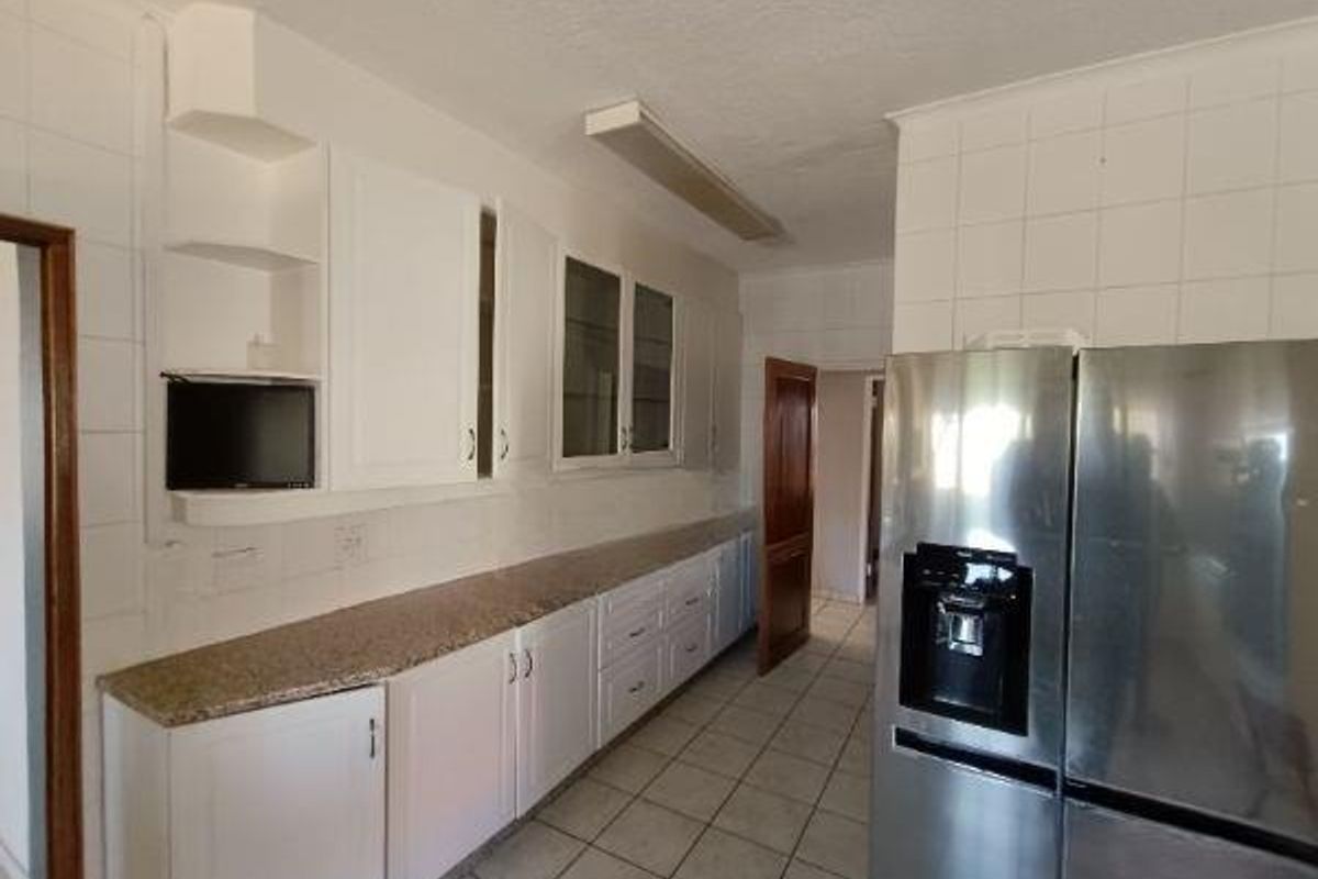 A functional kitchen featuring granite countertops, white cabinetry, and tiled wall finishes, offering a clean and practical workspace with potential for modern updates.