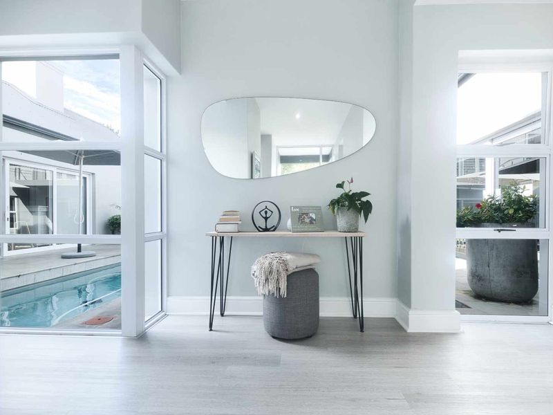 Bright and modern entrance hall featuring large windows with views of the outdoor pool area and clean, neutral finishes.