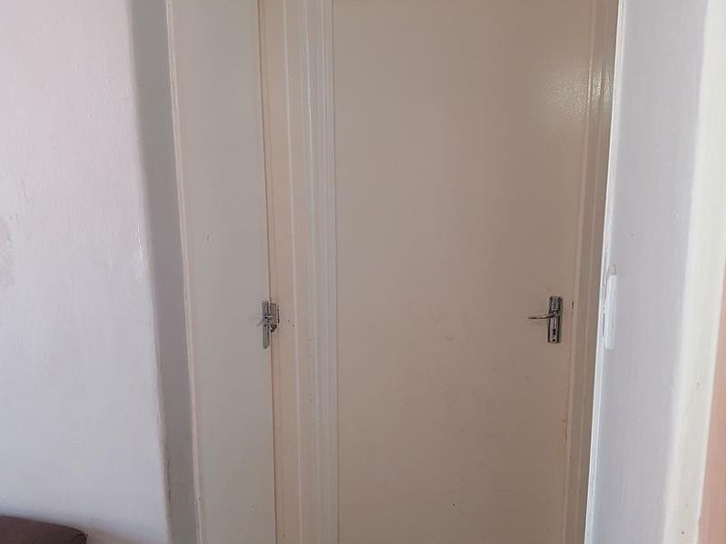 A functional hallway featuring tiled flooring and two internal doors, showing signs of general wear and tear.