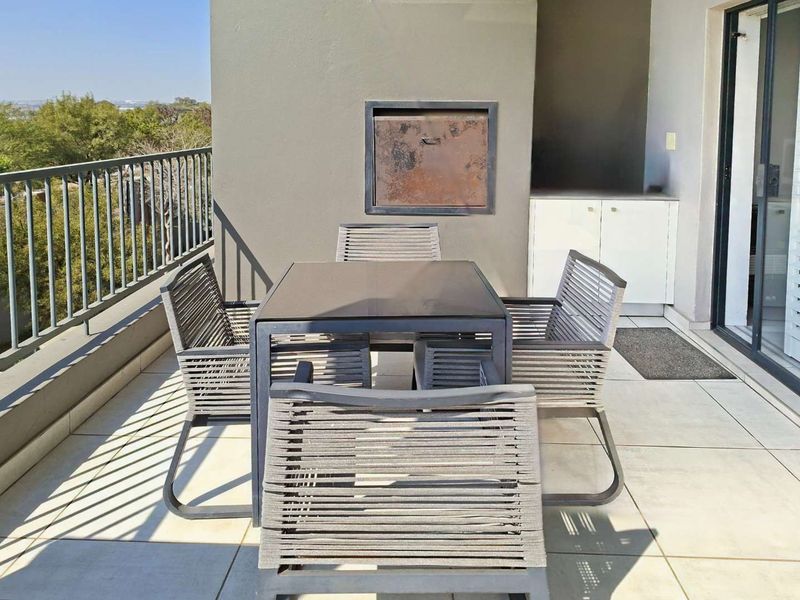 A balcony featuring tiled flooring, a built-in braai, and built-in cabinetry, offering an outdoor space for dining and relaxation.
