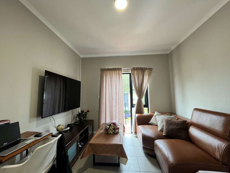 A comfortable living room featuring tiled flooring and a sliding glass door that provides access to an outdoor area.
