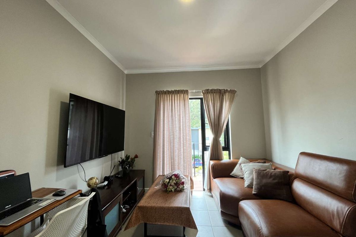 A comfortable living room featuring tiled flooring and a sliding glass door that provides access to an outdoor area.