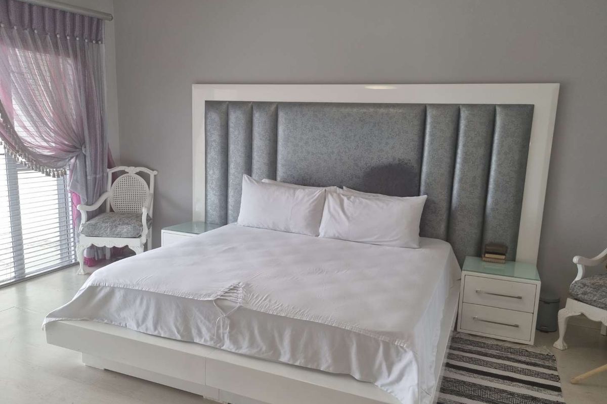 A well-maintained bedroom featuring a large, modern upholstered headboard and integrated bedside tables.