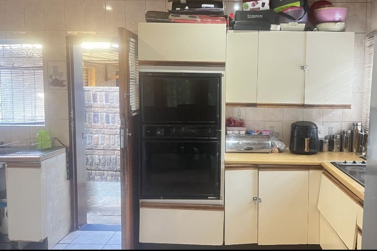 A dated kitchen featuring built-in cabinetry, a wall-mounted oven, and tiled backsplash, with direct access to an outdoor area.
