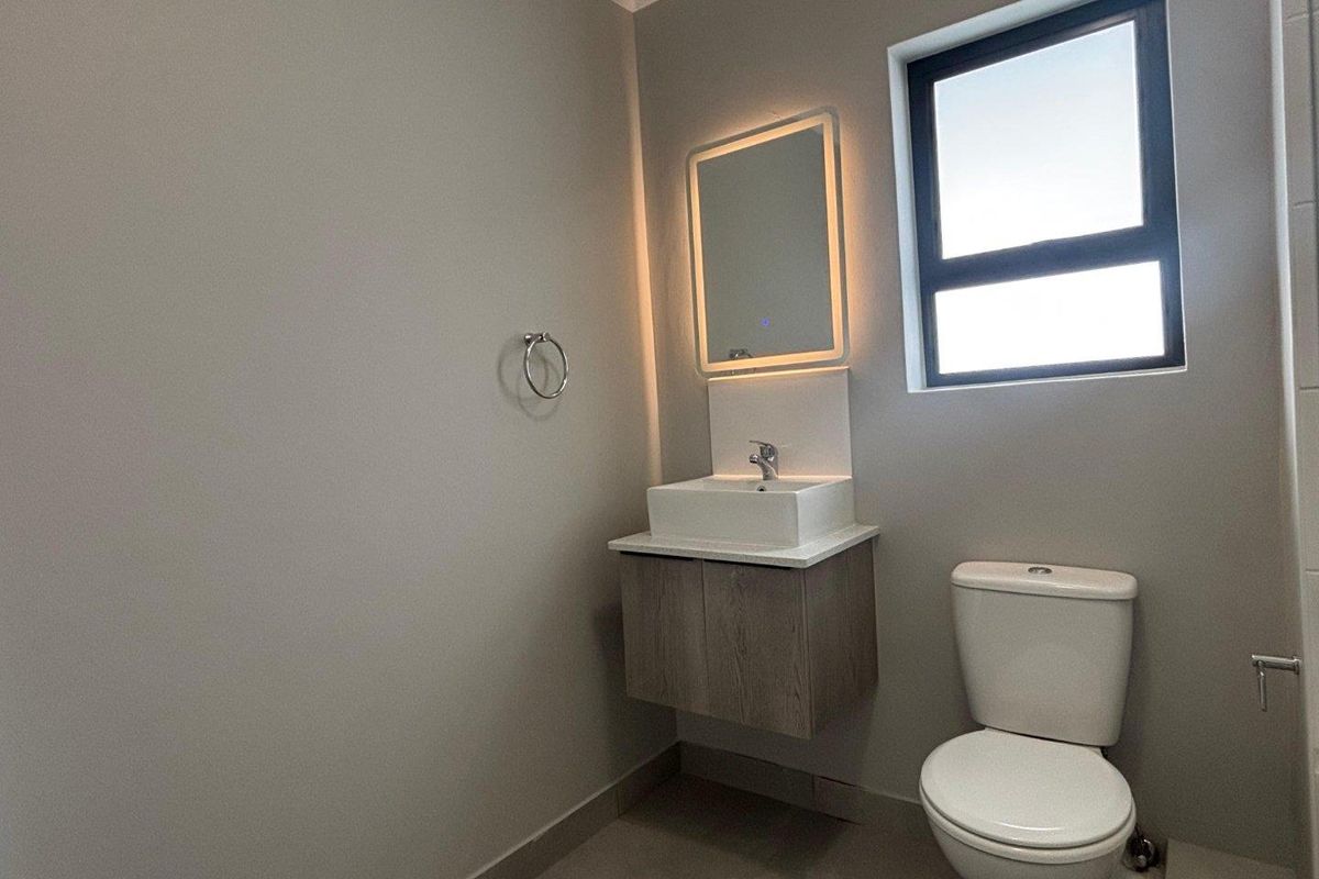 A modern bathroom featuring a floating vanity with a vessel sink, an illuminated mirror, and a standard toilet.