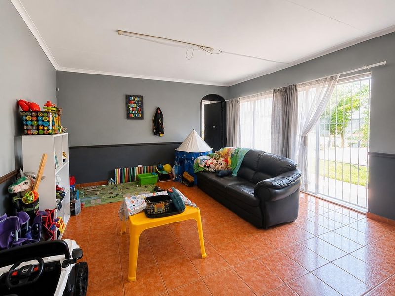 Living room featuring tiled flooring and a sliding glass door with security gate, providing access to the exterior.