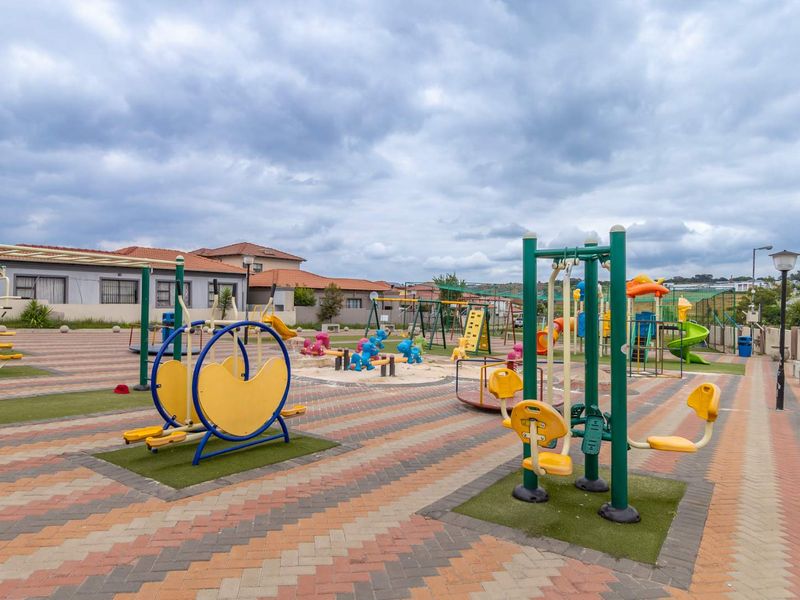 A communal outdoor recreational area featuring paved walkways, fixed playground equipment, and outdoor fitness stations within a residential cluster estate.