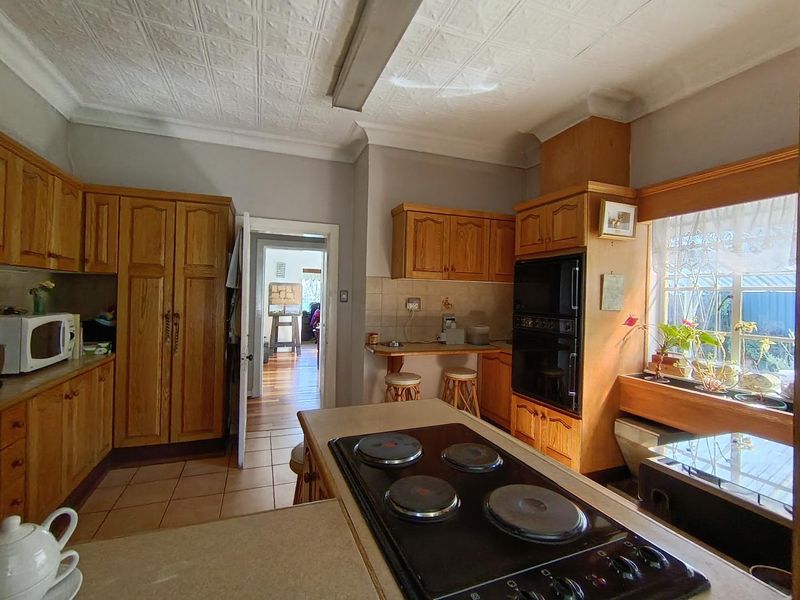 A traditional kitchen featuring wooden cabinetry, a built-in oven, an electric hob, and a unique pressed metal ceiling, offering a functional layout.
