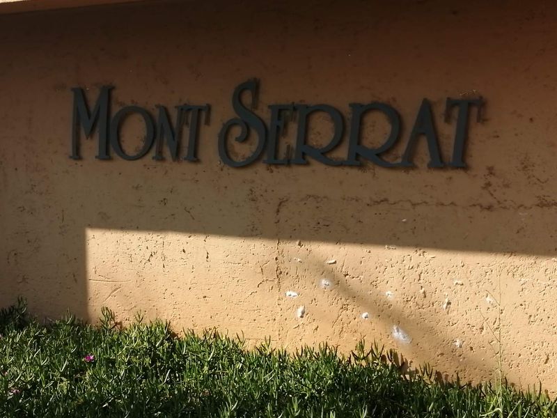 Exterior wall featuring the Mont Serrat building signage with visible wear and staining on the stucco finish.