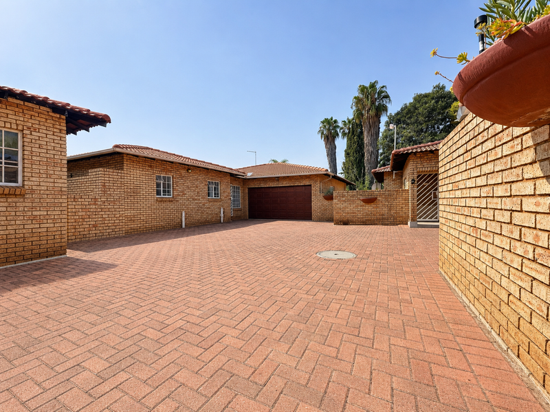 Spacious paved driveway leading to a secure garage, featuring classic face brick construction and well-maintained exterior finishes.