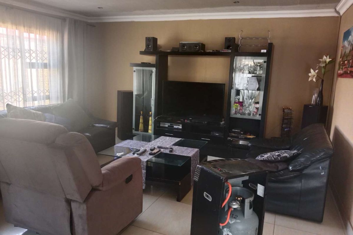 A comfortable living room featuring tiled flooring, neutral wall tones, and a built-in entertainment unit.