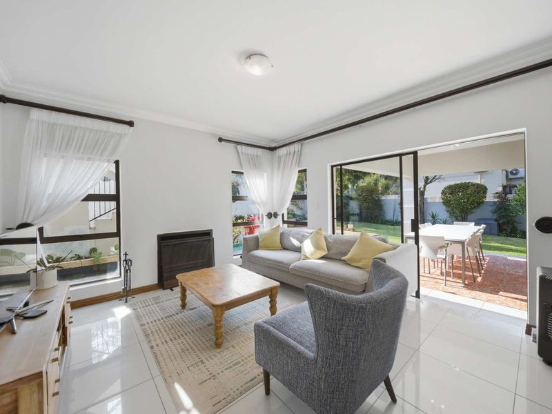 Bright living room featuring large sliding glass doors that open onto a patio, tiled floors, and a built-in fireplace.