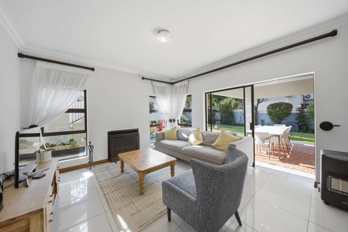 Bright living room featuring large sliding glass doors that open onto a patio, tiled floors, and a built-in fireplace.