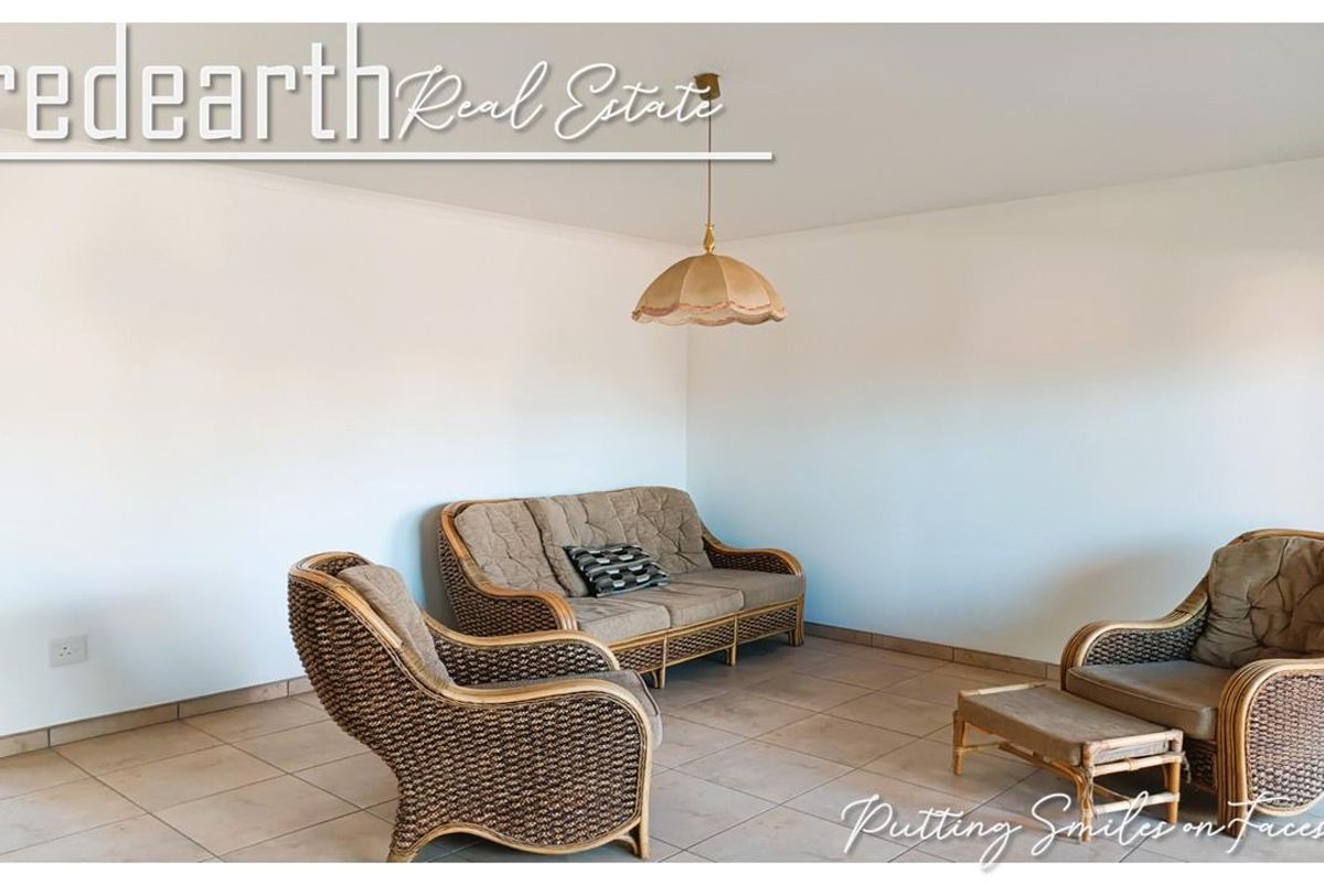 A bright living room featuring neutral tiled flooring and a central pendant light fixture, offering a clean and functional space.