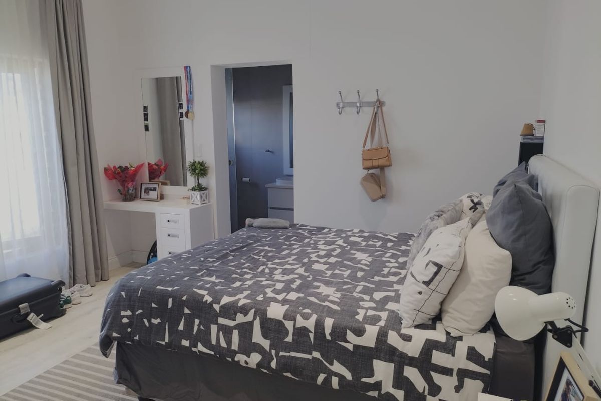 A well-maintained bedroom featuring neutral walls, light-toned flooring, and an en-suite bathroom access point.