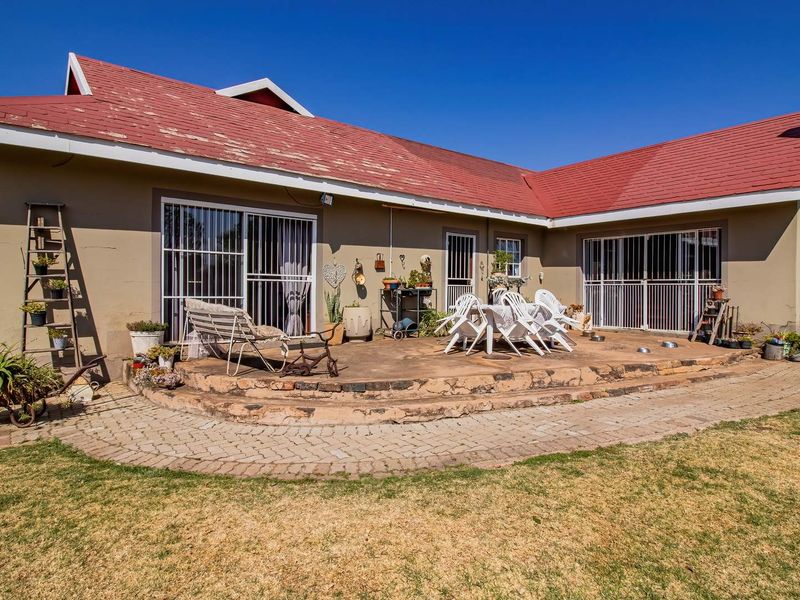 Rear view of the property featuring a paved patio area, stone chimney, and sliding door access to the main dwelling.
