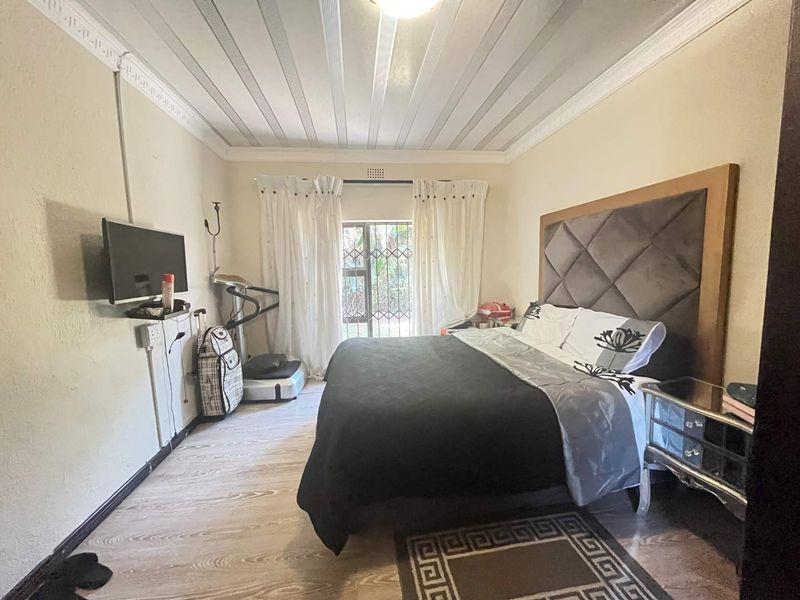 A bedroom featuring laminate flooring, crown molding, and a sliding door with a security gate leading to the exterior.