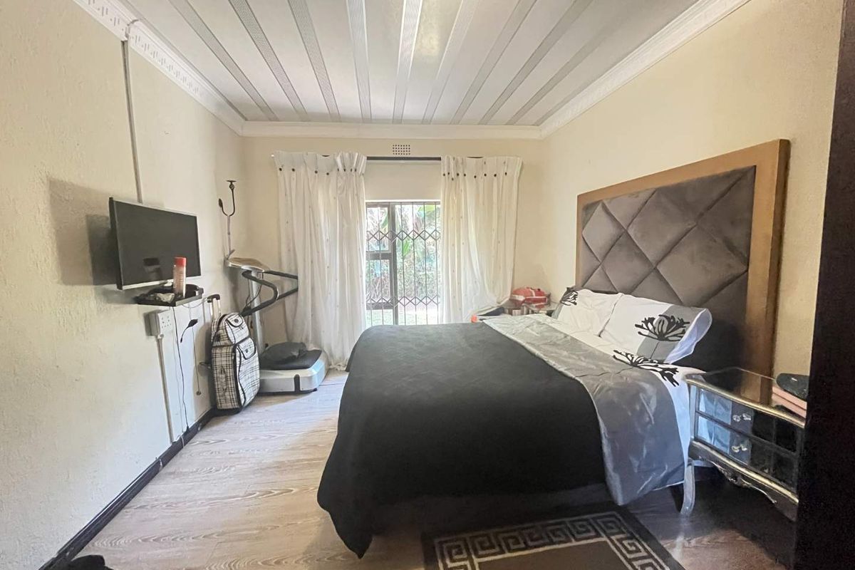 A bedroom featuring laminate flooring, crown molding, and a sliding door with a security gate leading to the exterior.