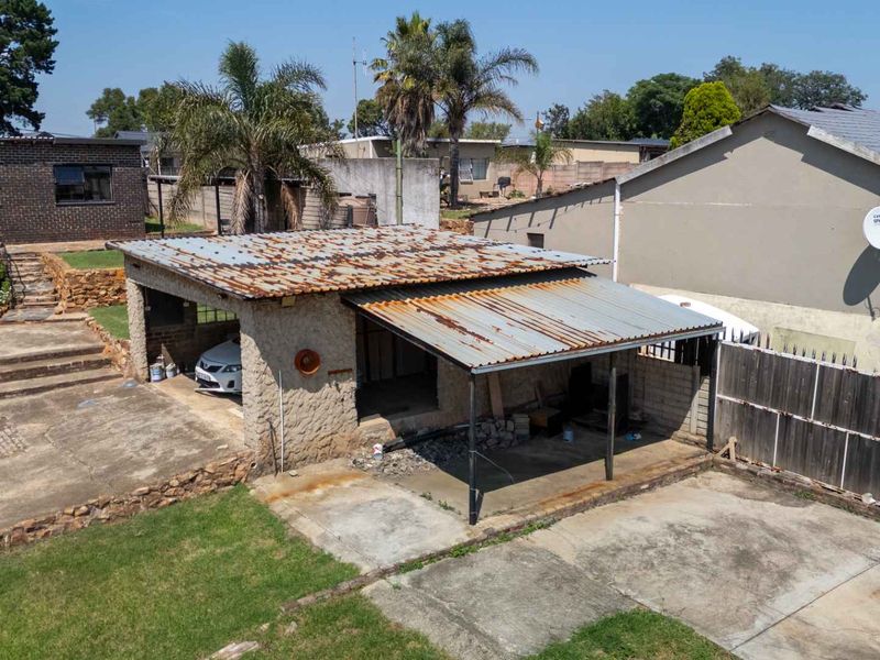 An elevated view of a detached garage structure featuring a weathered corrugated metal roof and concrete driveway area.